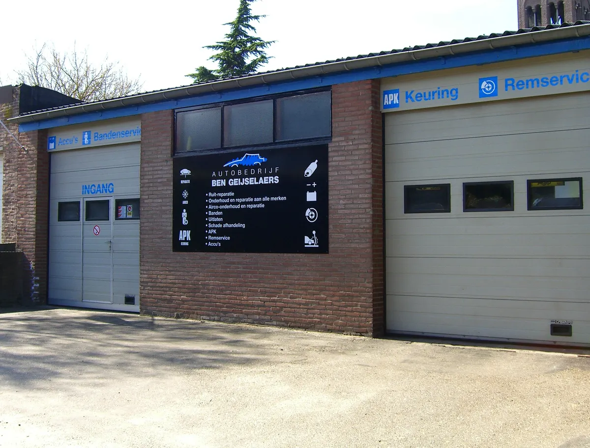 De gevel van Autobedrijf Ben Geijselaers met het bord met alle diensten en de BOVAG-vlag